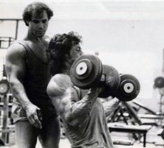 a man lifting a barbell in front of another man