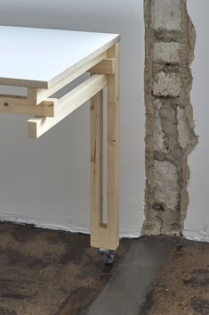 a white table sitting on top of a cement floor next to a brick wall with a hole in it