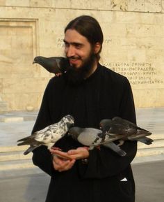 a man with long hair holding pigeons in his hands