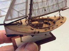 a hand is holding a small model sailboat