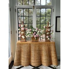 two vases with flowers are sitting on a table in front of a large window