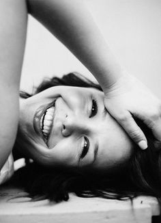 a black and white photo of a woman laying on the floor with her hands behind her head