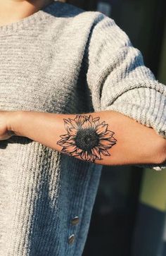 a woman's arm with a sunflower tattoo on the left side of her arm