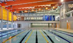 an indoor swimming pool with multiple lanes and glass doors on the ceiling, surrounded by windows