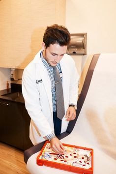 a male in a white coat and tie is looking at something on a red tray