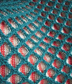 a crocheted blanket is shown with red and white stripes on the bottom half