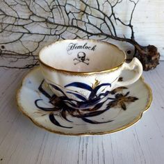 an antique tea cup and saucer decorated with blue flowers on a white wooden table