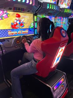 two people playing video games in a game room with arcade machines and neon signs on the walls