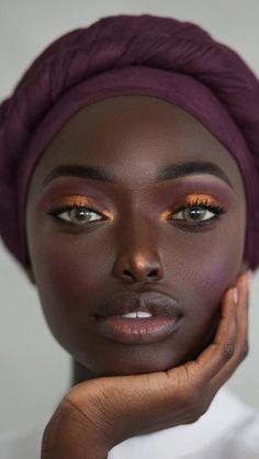 a woman with dark skin and orange eyes wearing a turban