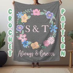 a woman holding up a gray blanket with flowers and the word s & t on it