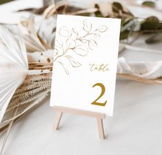 a white table number sitting on top of a wooden easel next to an umbrella