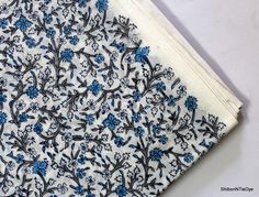 the fabric is blue and white with small flowers on it, along with an off - white background