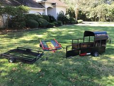 two trailers parked on the grass in front of a house with a trailer attached to it