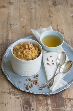 a bowl of oatmeal next to a cup of tea on a plate