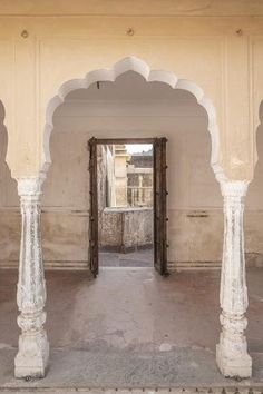 an archway in the middle of a building with pillars and arches on either side, leading to another room