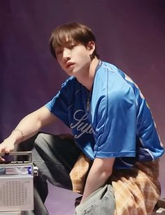 a young man sitting on top of a table next to a radio