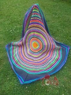 a crocheted blanket is laying on the grass