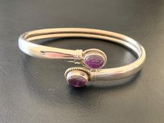 925 Sterling Silver Amethyst Bangle Stylish easy-wearing bangle Solid sterling silver bangle with amethyst gemstones 2 bezel set amethyst cabochon stones sit at the ends of the bangle Ends of bangle can be pulled apart for ease of putting on and taking off Highest quality guaranteed 925 Sterling Silver - 92.5% pure silver Specifications:    Color: Silver & Dark Purple  Material: 925 Sterling SIlver & Amethyst  Dimensions of gemstones: 8 mm x 6 mm approximately Inner Dimensions: 60 mm x 47 mm approximately Outer Dimensions of bangle: 65 mm x 55 mm approximately Width of Bangle: 5 mm approximately Weight: 12.7 grams approximately Package Includes: 1 x sterling silver gemstone bangle with complimentary jewellery pouch Purple Amethyst Bangle, Amethyst Gemstone Bangle, Purple Gemstone Bangle For Formal Occasions, Formal Purple Gemstone Bangle, Elegant Silver Amethyst Bangle, Silver Amethyst Bangle Bracelets, Silver Amethyst Bangle Bracelet, Sterling Silver Amethyst Bracelet With Gemstone, Silver Amethyst Gemstone Bangle