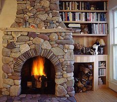 a stone fireplace in a living room next to a bookshelf with shelves full of books