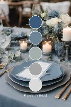 the table is set with blue and gray plates, silverware, candles and flowers