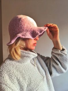 a woman wearing a pink hat while standing next to a wall