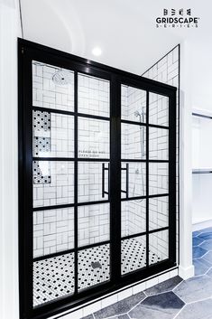 a bathroom with black and white tiles on the wall, glass doors to separate it from the rest of the room