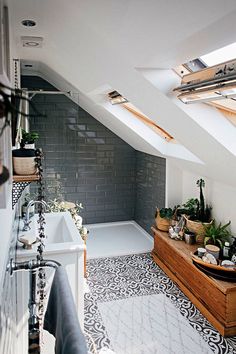 an attic bathroom with black and white tile flooring, skylights, and bathtub