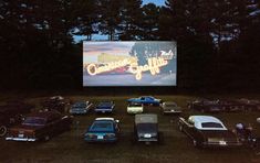 a group of cars parked in front of a movie screen