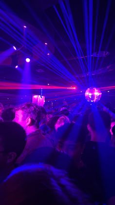 a crowd of people in a dark room with purple and blue lights