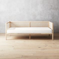 a white couch sitting on top of a hard wood floor next to a gray wall