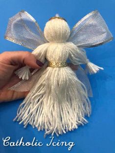 a white angel ornament being held up by someone's hand on a blue background