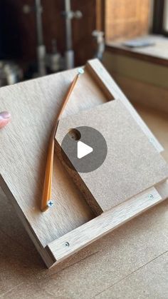 a person holding a wooden box with a pencil in it and an arrow on the inside