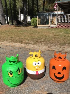 three plastic trash cans with faces painted on them sitting in the middle of a driveway