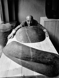 a man laying on top of a wooden floor next to two large oval shaped objects