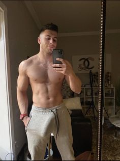 a shirtless man taking a selfie in front of a mirror with his cell phone