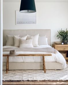 a bed with white linens and pillows in a small room next to a wooden table