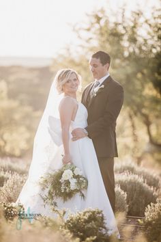 a bride and groom standing in the middle of lavender fields