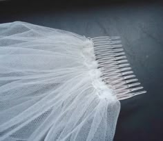 a white veiled comb laying on top of a black surface