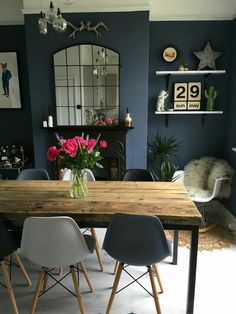 a dining room table with chairs and a vase full of flowers on top of it