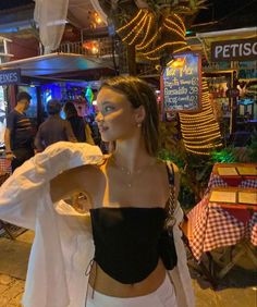 a woman in white pants and crop top standing on the street