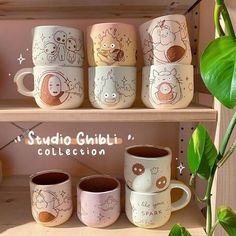 coffee mugs are sitting on the shelf in front of a potted green plant