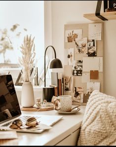 an open laptop computer sitting on top of a white desk next to a cup of coffee