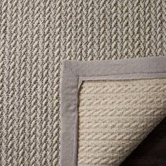 a close up view of the corner of a rug with a gray and white border