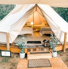 the inside of a tent with two beds in it and plants growing out of pots