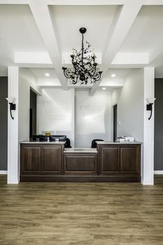 an empty reception room with a chandelier hanging from the ceiling and wood flooring