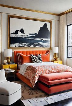 an orange and white bed in a bedroom with a painting on the wall above it