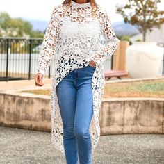 a woman in jeans and a white top is walking down the street with her hand on her hip