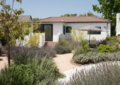 a white house surrounded by plants and trees