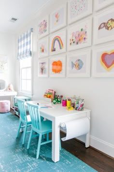 a child's playroom with blue chairs and artwork on the wall above it