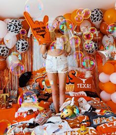 a woman standing on top of a bed surrounded by balloons and confettis